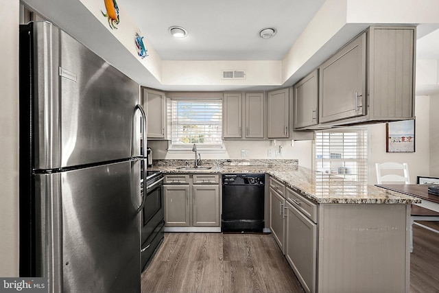 kitchen featuring black appliances, sink, gray cabinets, dark hardwood / wood-style flooring, and kitchen peninsula