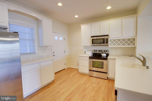 kitchen featuring white cabinets, sink, appliances with stainless steel finishes, and light hardwood / wood-style flooring