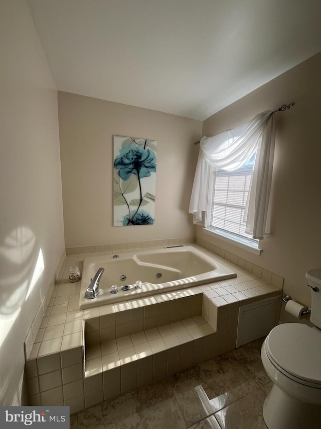 bathroom featuring tiled tub and toilet