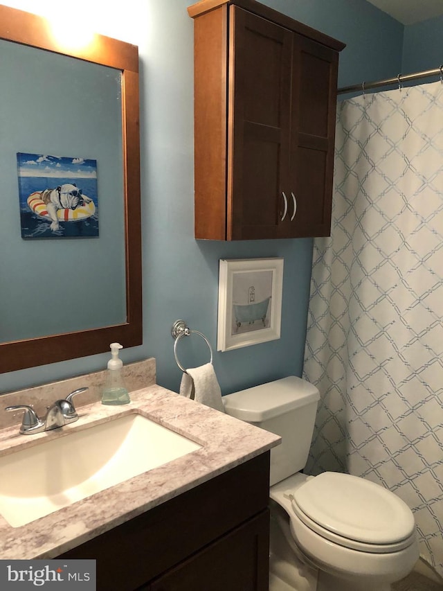 bathroom with a shower with shower curtain, vanity, and toilet