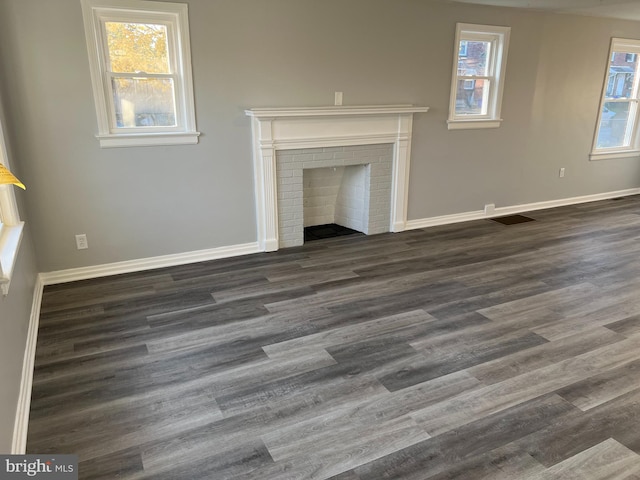 unfurnished living room with dark hardwood / wood-style floors and a brick fireplace