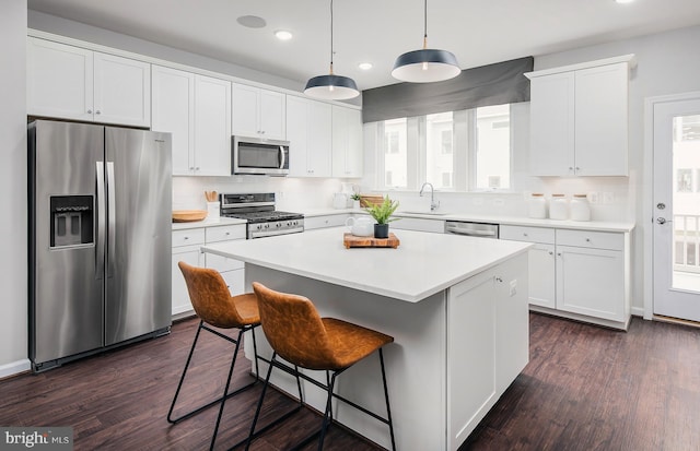 kitchen with dark wood-type flooring, a center island, white cabinets, and stainless steel appliances