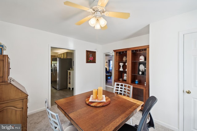 carpeted dining area with ceiling fan