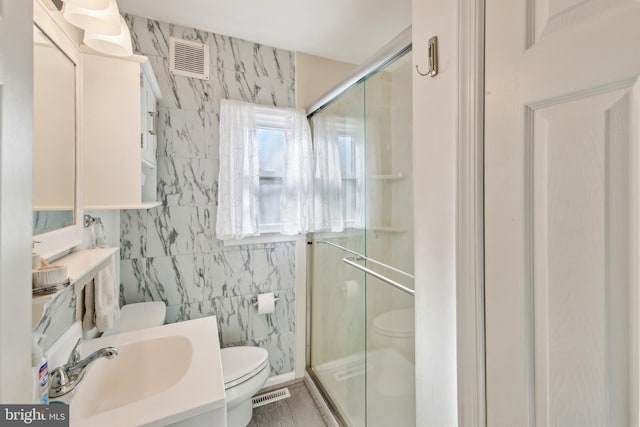 bathroom featuring toilet, vanity, tile walls, and walk in shower