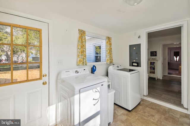 laundry area with separate washer and dryer, a wealth of natural light, electric panel, and light wood-type flooring