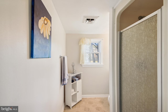 bathroom featuring a shower with door and toilet