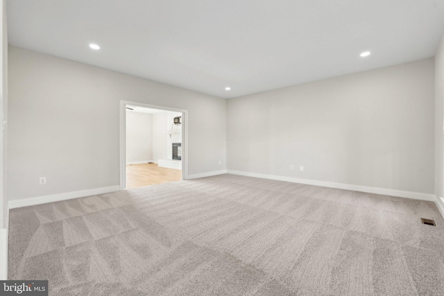 carpeted empty room with recessed lighting, baseboards, visible vents, and a fireplace