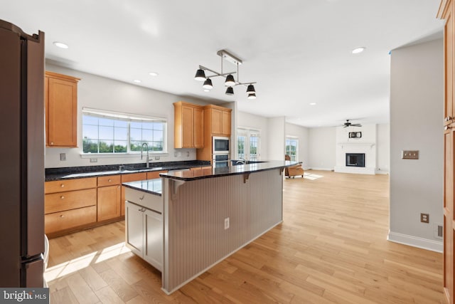 kitchen featuring appliances with stainless steel finishes, light wood-type flooring, a sink, open floor plan, and a breakfast bar