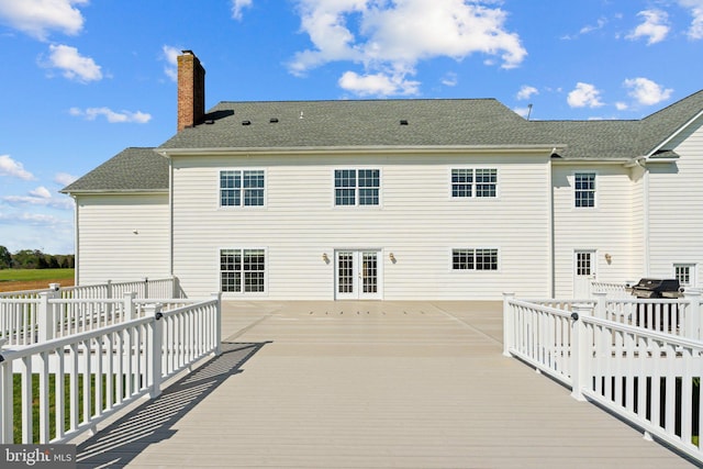 rear view of house with french doors, fence, a wooden deck, and a chimney