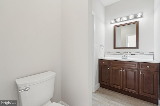bathroom featuring vanity, baseboards, and toilet