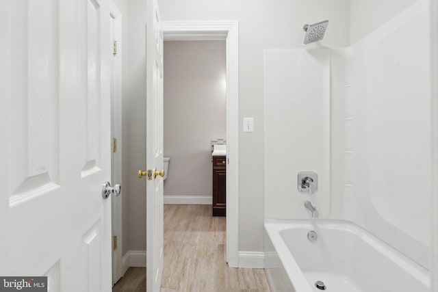 bathroom featuring baseboards, shower / bathing tub combination, wood finished floors, and vanity