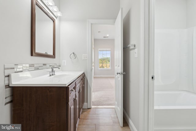 bathroom featuring baseboards, a tub to relax in, tile patterned flooring, and vanity
