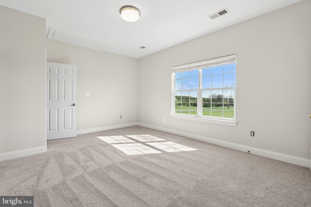 carpeted empty room featuring baseboards, attic access, and visible vents