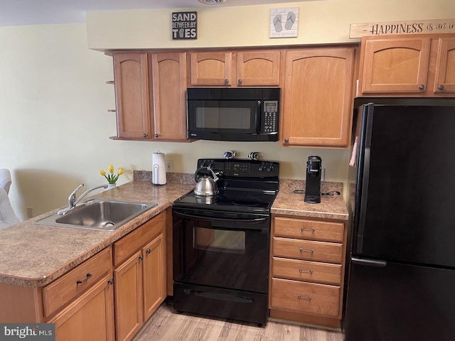 kitchen with black appliances, kitchen peninsula, sink, and light hardwood / wood-style flooring