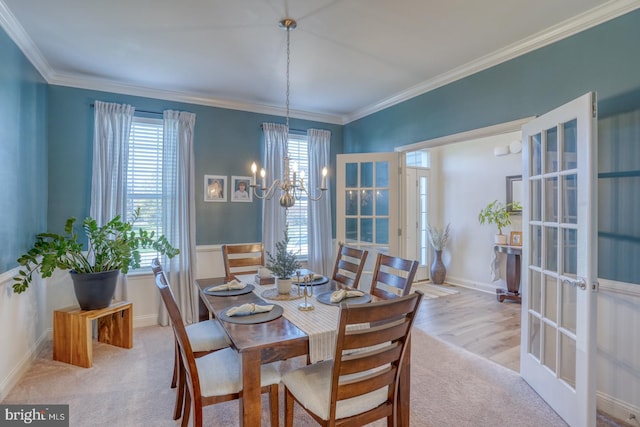 dining space featuring a healthy amount of sunlight, ornamental molding, light hardwood / wood-style flooring, and french doors