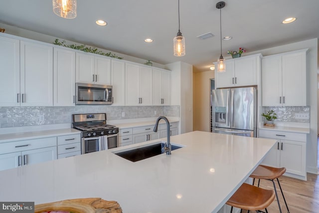 kitchen with decorative light fixtures, sink, white cabinetry, and stainless steel appliances