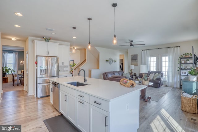 kitchen featuring sink, stainless steel appliances, plenty of natural light, and a center island with sink