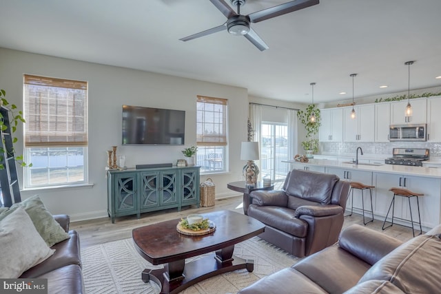 living room with ceiling fan, light wood-type flooring, and sink