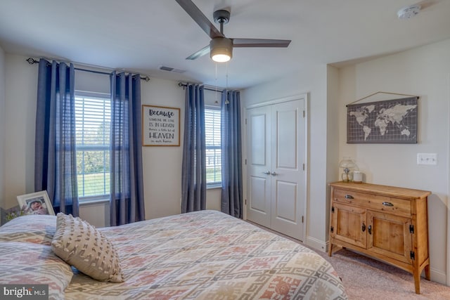 carpeted bedroom with multiple windows, ceiling fan, and a closet