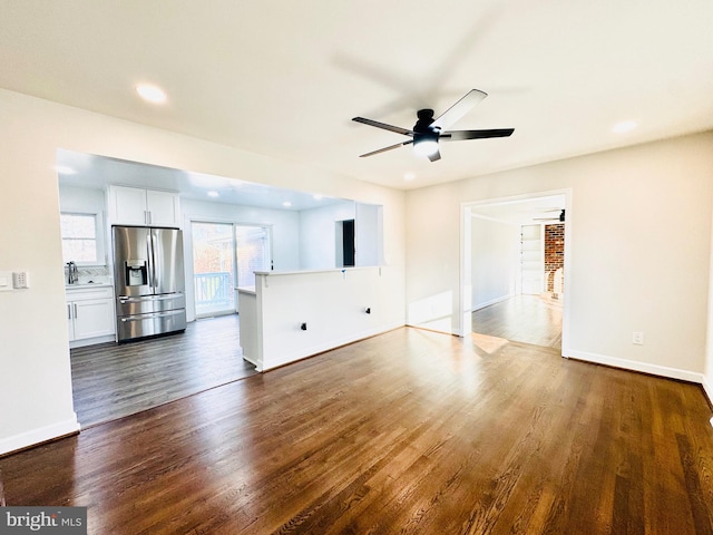 unfurnished living room with dark hardwood / wood-style flooring, ceiling fan, and sink