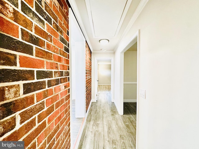 hallway with ornamental molding, brick wall, and light hardwood / wood-style flooring