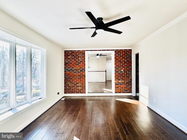 unfurnished room featuring a wealth of natural light, wood-type flooring, and brick wall