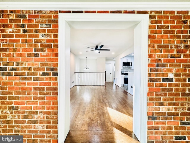 corridor with hardwood / wood-style flooring and brick wall