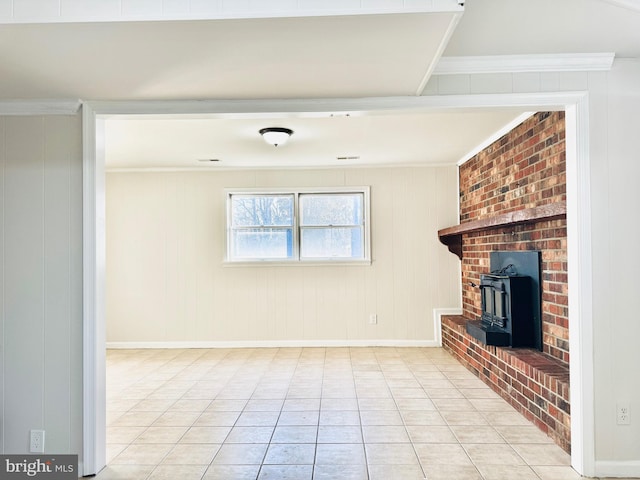 unfurnished living room with a wood stove, crown molding, wooden walls, and light tile patterned flooring