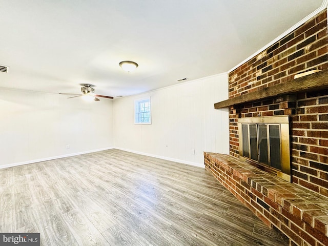 unfurnished living room featuring hardwood / wood-style floors, ceiling fan, crown molding, and a fireplace