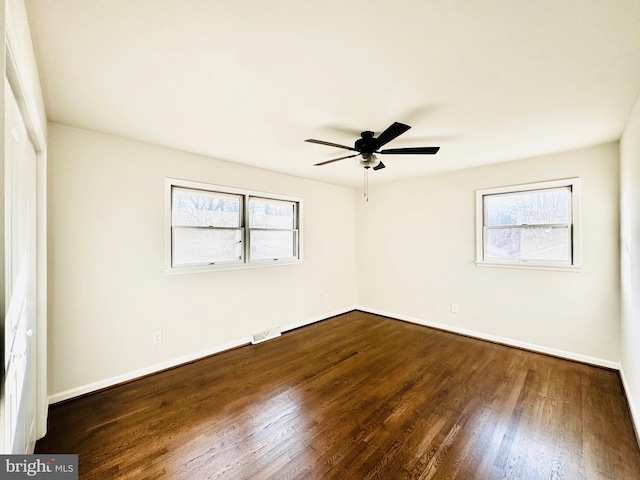 empty room featuring ceiling fan, plenty of natural light, and dark wood-type flooring