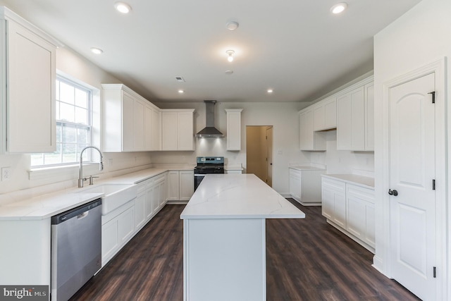 kitchen featuring a center island, black gas stove, wall chimney range hood, stainless steel dishwasher, and white cabinetry