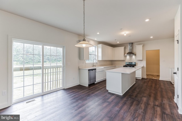 kitchen with a healthy amount of sunlight, dark hardwood / wood-style floors, a kitchen island, and wall chimney exhaust hood