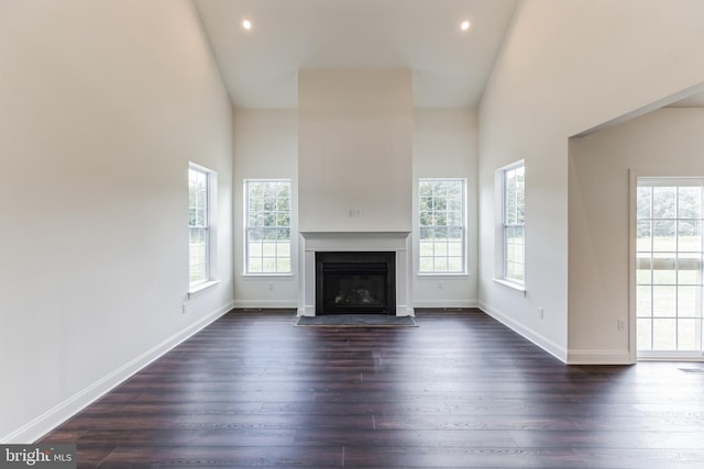 unfurnished living room featuring plenty of natural light, dark hardwood / wood-style flooring, and high vaulted ceiling