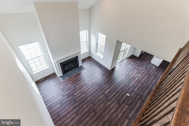 unfurnished living room featuring a towering ceiling and dark wood-type flooring