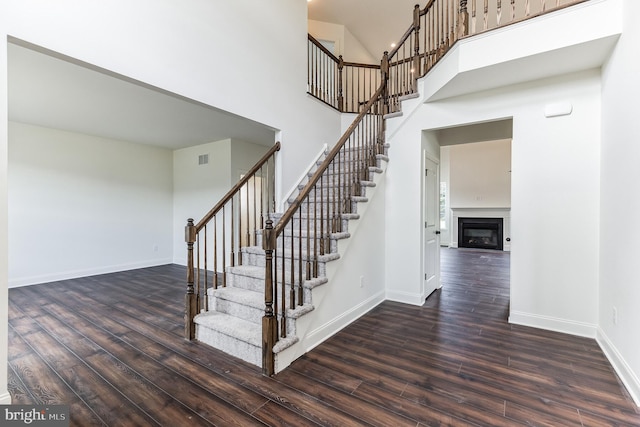 staircase with wood-type flooring and a high ceiling