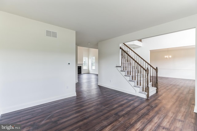 empty room featuring dark hardwood / wood-style flooring and a notable chandelier