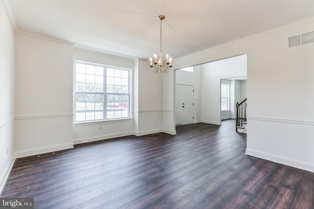 empty room featuring dark hardwood / wood-style floors, ornamental molding, and an inviting chandelier