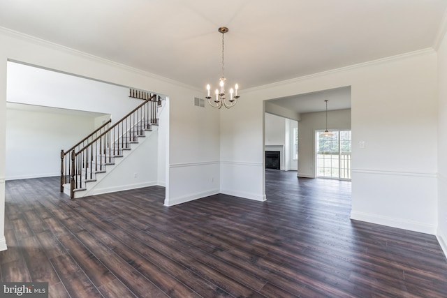 spare room with crown molding, dark wood-type flooring, and a chandelier