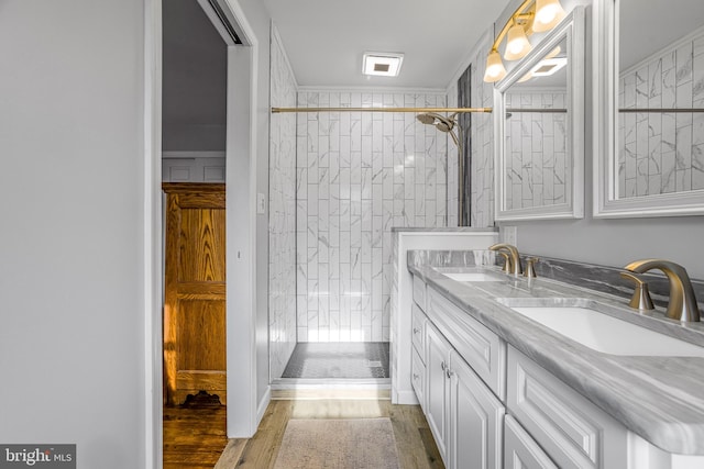 bathroom featuring hardwood / wood-style floors, vanity, crown molding, and tiled shower