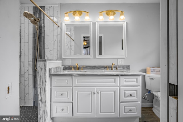 bathroom with tiled shower, hardwood / wood-style floors, vanity, and toilet