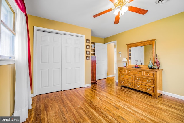 bedroom with a closet, light hardwood / wood-style floors, and ceiling fan