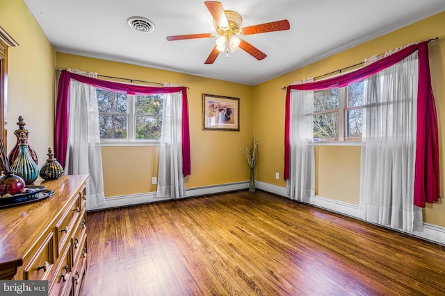 interior space featuring hardwood / wood-style flooring, ceiling fan, a healthy amount of sunlight, and baseboard heating