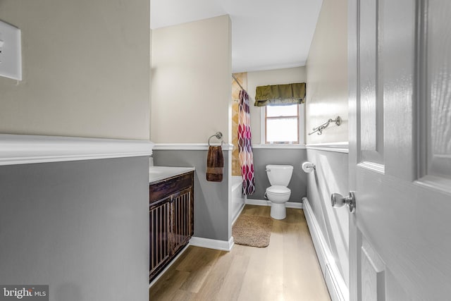 full bathroom with hardwood / wood-style floors, vanity, shower / bath combination with curtain, toilet, and a baseboard radiator