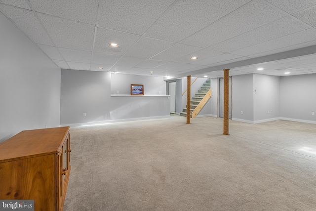 basement with a paneled ceiling and light carpet