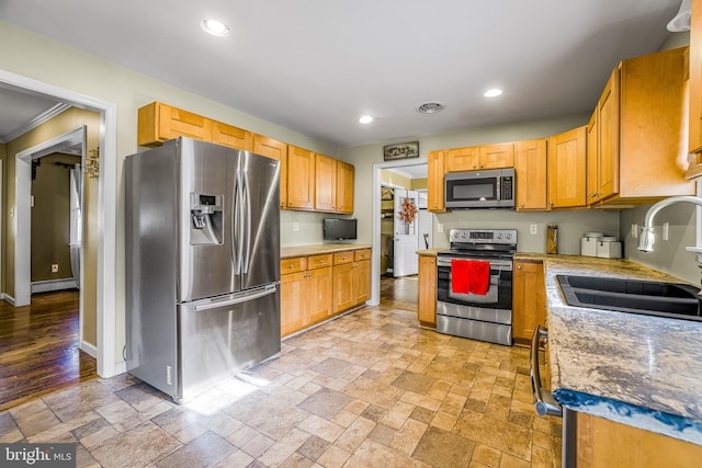 kitchen featuring appliances with stainless steel finishes, crown molding, a baseboard heating unit, sink, and light hardwood / wood-style flooring