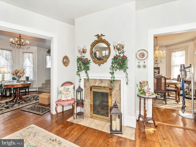 sitting room featuring a fireplace, wood-type flooring, and a chandelier