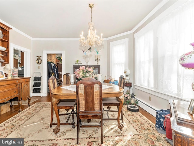 dining area with ornamental molding, a notable chandelier, and light hardwood / wood-style flooring