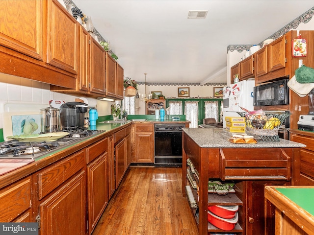 kitchen with pendant lighting, hardwood / wood-style floors, black appliances, and sink