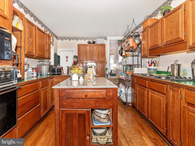 kitchen with wall oven, decorative backsplash, light hardwood / wood-style flooring, and a center island