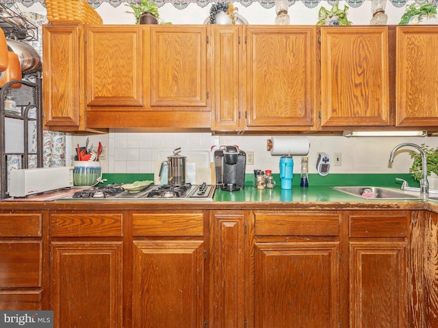 kitchen featuring stainless steel gas stovetop, sink, and decorative backsplash